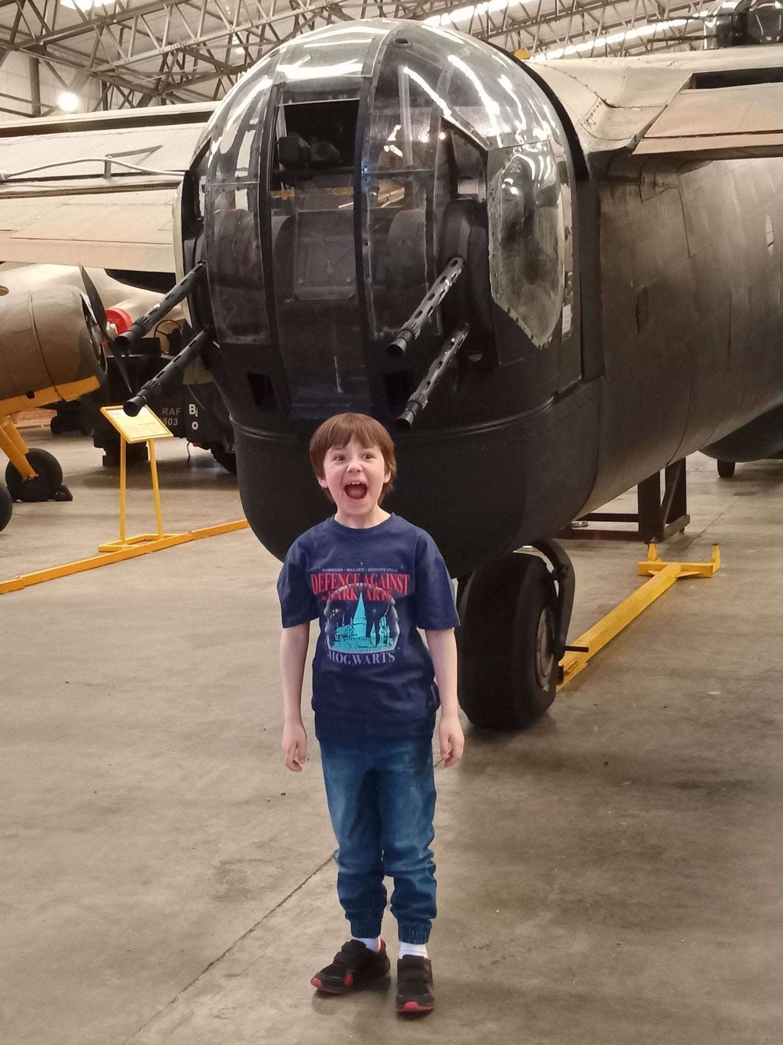 My son Alex grinning in front of a bomber and its glass nose turret